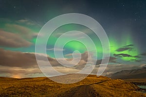 Aurora Borealis in Iceland northern lights bright beams rising green over hiking path