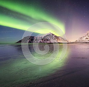 Aurora borealis on the Lofoten islands, Norway. Green northern lights above mountains. Night sky with polar lights. Night winter l