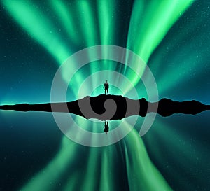 Aurora borealis, man and lake with sky reflection in water