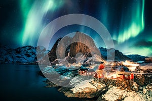 Aurora borealis, Northern lights over mountain with fishing village on coastline at Hamnoy, Lofoten islands