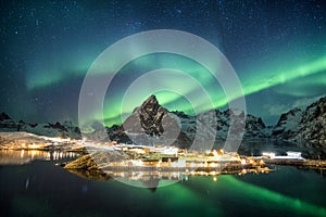 Aurora borealis over mountains in scandinavian village glowing