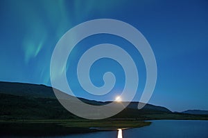 Aurora Borealis over the northern lake, early summer morning. Yamal, Russia