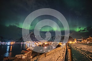 Aurora borealis over scandinavian village light shining in winter