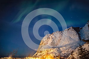 Aurora borealis over snow mountain in Reine town at Lofoten Islands