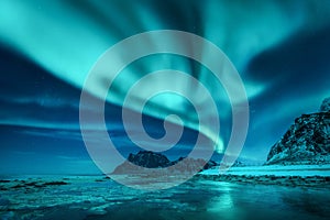 Aurora borealis over the snowy mountains and sandy beach