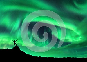 Aurora borealis and silhouette of a man with raised up arms