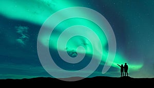 Aurora borealis and silhouette of man and woman