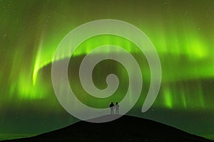 Aurora borealis and silhouette of standing lovers. Jokulsarlon, Iceland. Aurora and happy man.