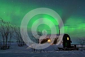 Aurora borealis and stars in the sky above a small house