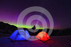 Aurora Borealis and tents on snow mountain