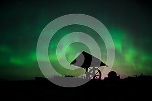 Aurora in the starry sky above the well in the tundra