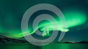 Aurora whirling over the fjord reflecting in the sea