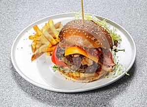 Aussie Beef Burger include cheese slice, tomato, cabbage and chilli sauce with french fries served in dish isolated on background