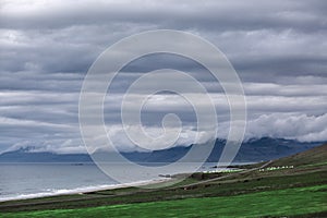 The austere Icelandic landscape with field in the foreground and the mountains and the fjords in the background