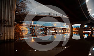 Austin skyline at night and Lamar pedestrial Bridge with bright illuminated buildings reflecting in Lady Bird Lake