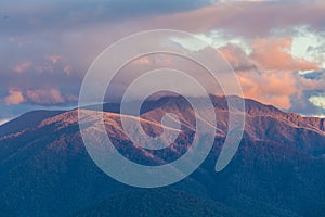 Australian Alps in orange sunset light and low clouds.