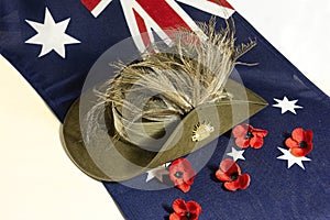 Australian army diggers slouch hat on flag with poppies.