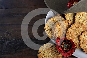 Australian army slouch hat and traditional Anzac biscuits on dark recycled wood with copy space photo
