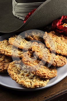 Australian army slouch hat and traditional Anzac biscuits on dark recycled wood - vertical close up photo