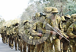 Australian army soldiers marching road to base in camouflage bush war tactics training