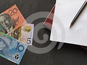 Australian banknotes, black pen and books