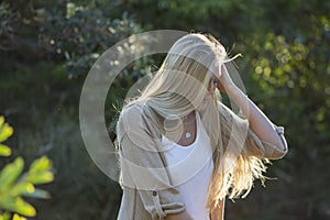 Australian Beauty with Long Blond Hair Looks Down with Sun Streaming Through Hair