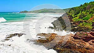 Australian coast, view from a cliff to the blue ocean with a rocky shore on a sunny day. Sea landscape, waves crashing on rocks