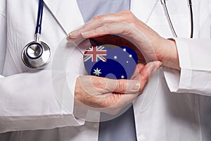 Australian doctor holding heart with flag of Australia background. Healthcare, charity, insurance and medicine concept