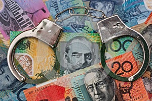 Australian dollar banknotes with handcuffs on wooden table