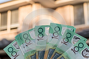 Australian dollars 100 banknotes with blurred resedential building on background. Finance and mortgage concept photo