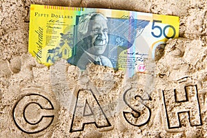 Australian fifty dollar note in the sand on the beach.