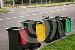 Australian garbage wheelie bins with colourful lids lined up on the street