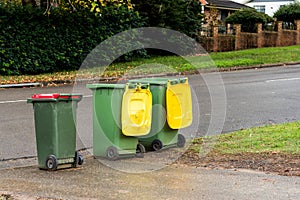 Australian garbage wheelie bins with colourful lids for recycling and general household waste lined up on the street for council