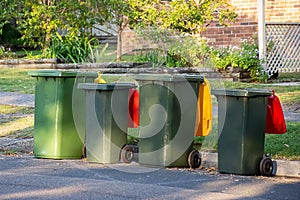Australian garbage wheelie bins with colourful lids for recycling and general household waste lined up on the street kerbside photo