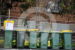 Australian garbage wheelie bins with colourful lids for recycling household waste on a street kerbside for council rubbish