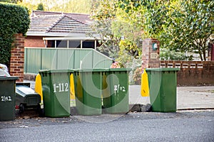 Australian garbage wheelie bins with colourful lids for recycling waste lined up on the street kerbside for council collection