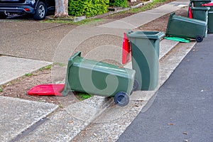 Australian garbage wheelie bins red lids for general waster stay and lie down on the street kerbside photo