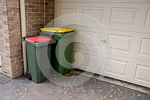 Australian garbage wheelie bins with red and yellow lids for general and recycling household waste near the resedential building