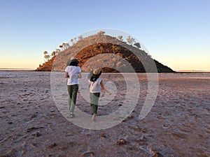 Australian girls walking into the landscape view of lake Ballard near Menzies, Western Australia