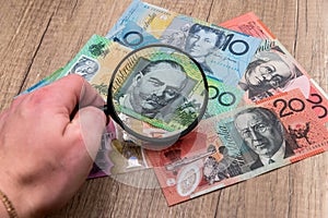 Australian notes under a magnifying glass in hand