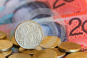 Australian one dollar coin with a background of notes and coins.