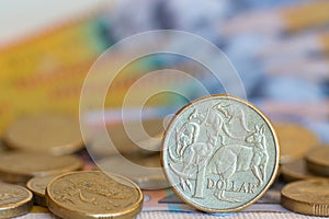 Australian one dollar coin with a background of notes and coins.