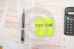 Australian tax forms with pen and calculator. Financial document. Tax time on a yellow sticker. View from above.