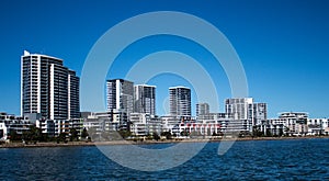 Australian waterside houses and condominiums with rock sea wall against blue sky