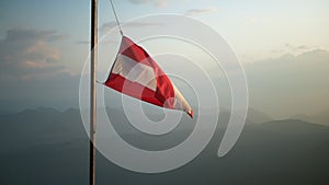 Austria flag in the wind in mountain sunset shot