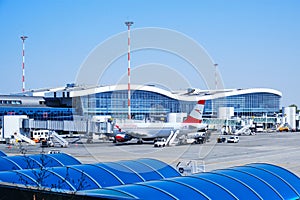 Austrian Airlines airplane docked to a passengers boarding bridge at Henri Coanda International Airport Bucharest on a clear day.