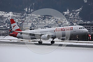 Austrian Airlines plane landing on snowy runway, Innsbruck Airport