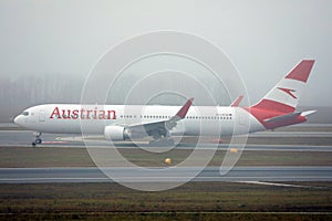 Austrian Airlines plane doing taxi on taxiway, fog