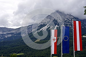 Austrian and EU flags flying with Heho Salve mountain behind. Söll, Austria.