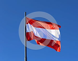 Austrian flag waving in the blue cloudless sky